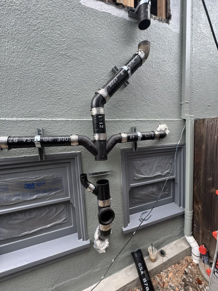 Exterior PVC venting and drain stack installation on building exterior