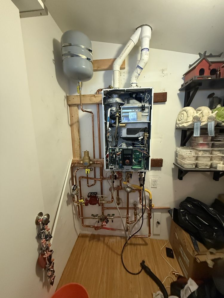 Completed tankless water heater installation with copper piping and expansion tank in mechanical closet